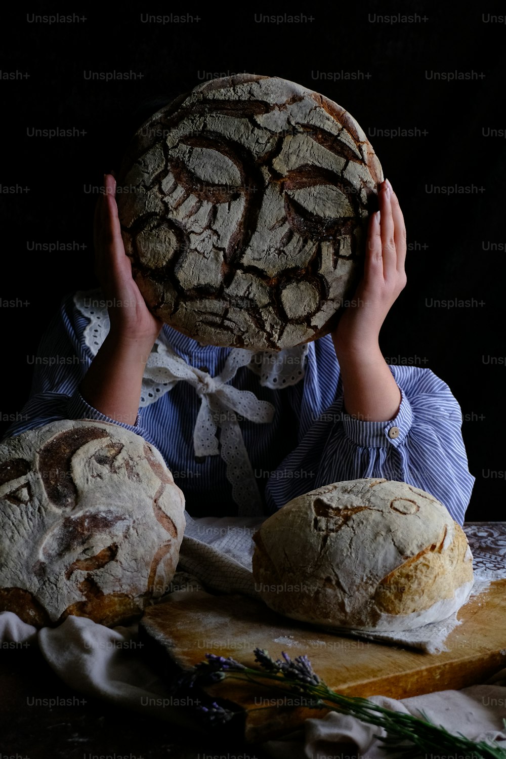 eine Person, die einen Laib Brot über ihr Gesicht hält