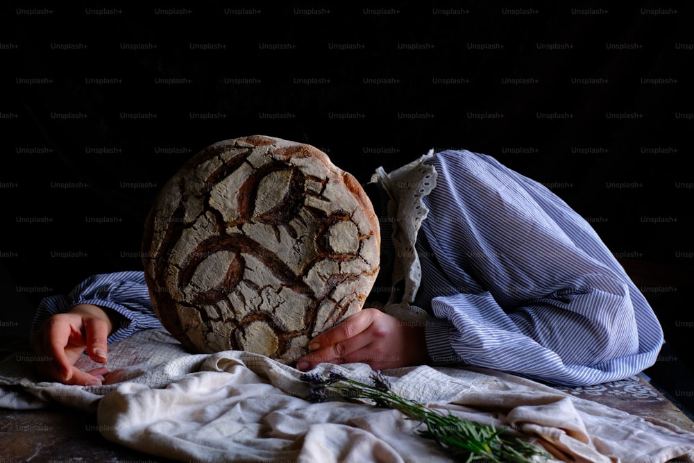 a person holding a large piece of bread on top of a table