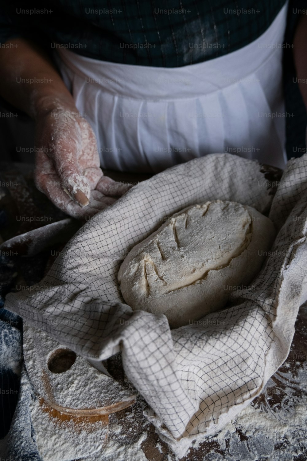 흰 앞치마를 입은 사람이 빵을 만들고 있다