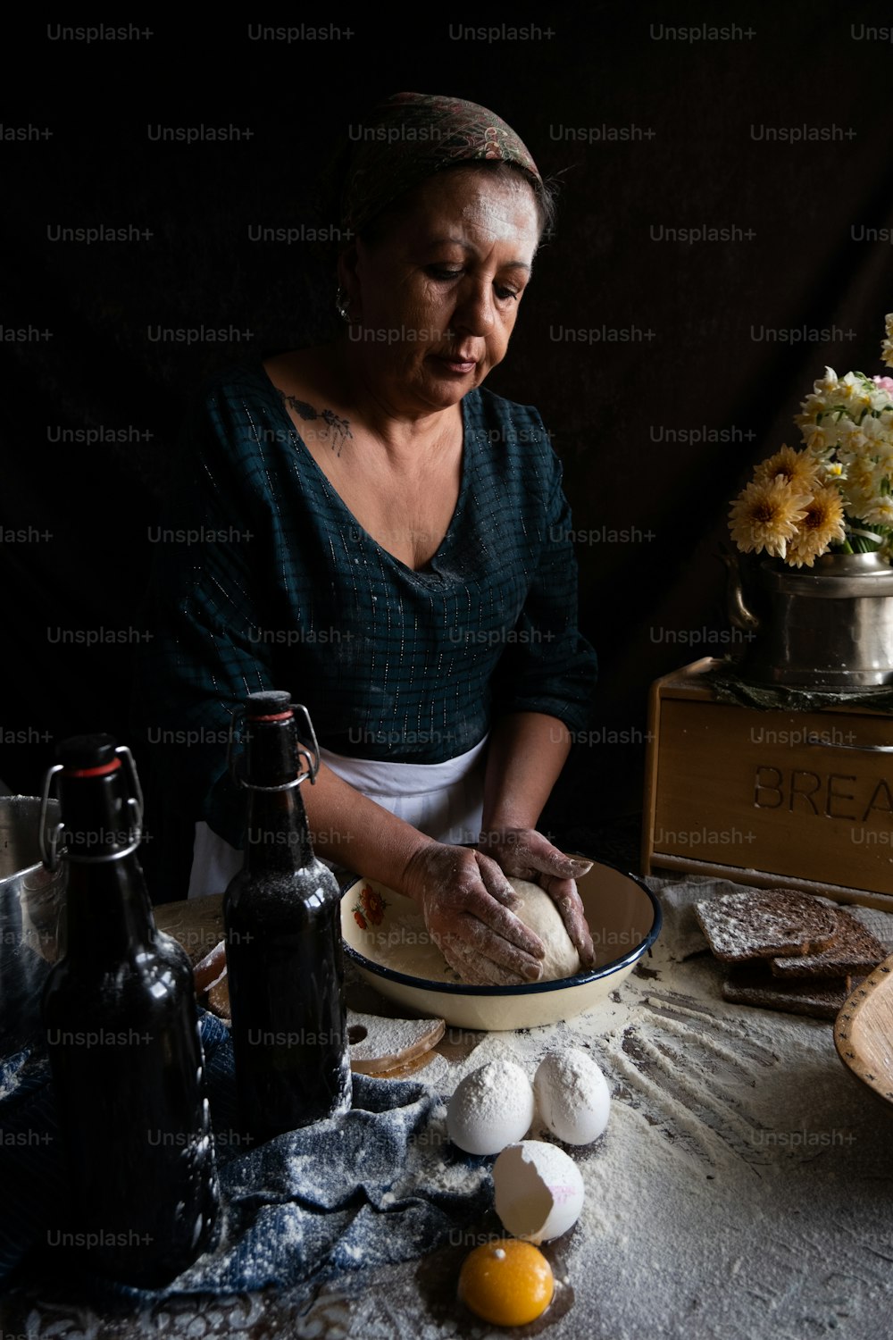 Une femme en chemise noire pétrit de la pâte sur une table