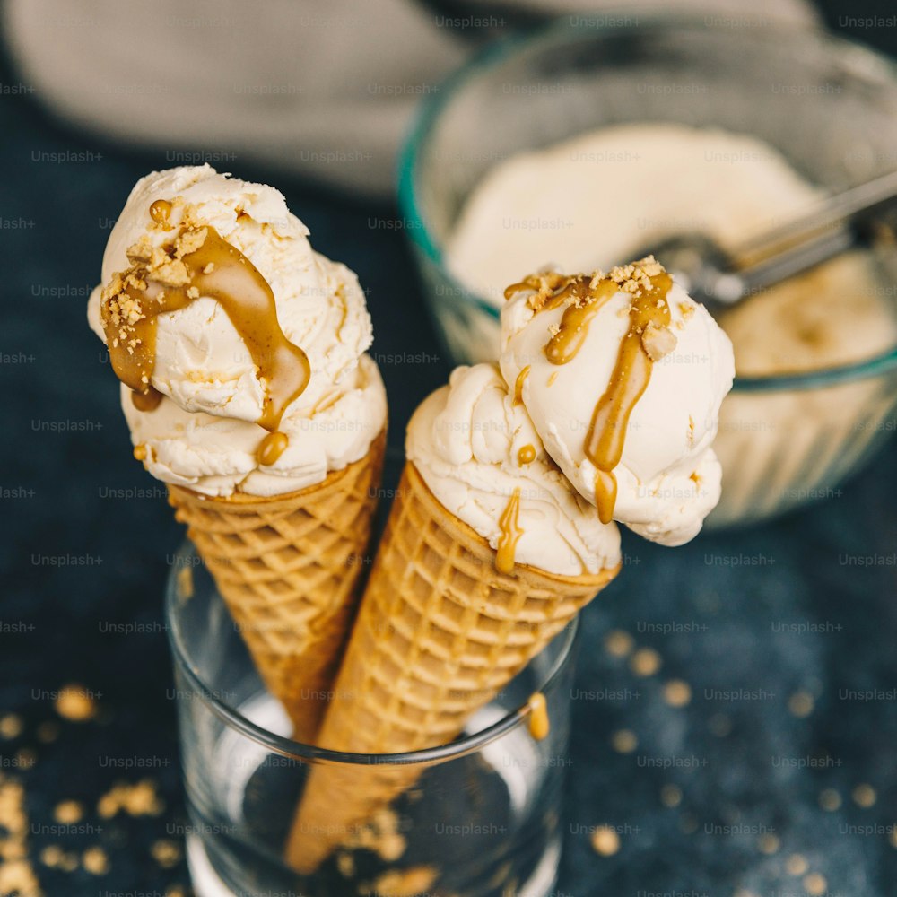 two ice cream cones with caramel drizzle on them