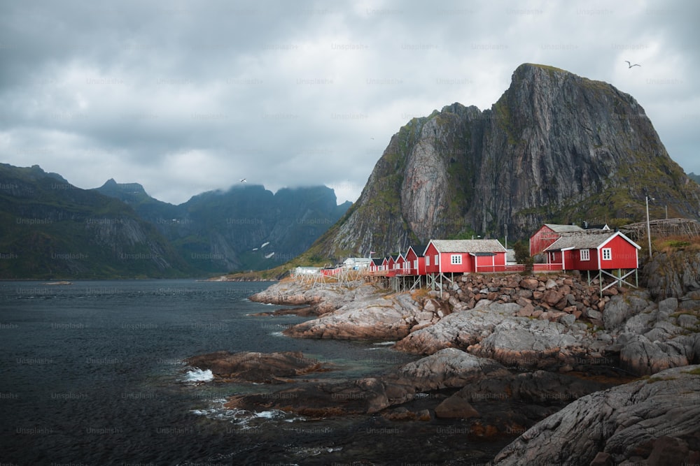 a group of red houses sitting on top of a rocky shore