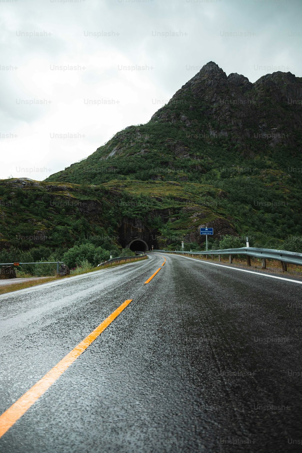 Une route mouillée avec une montagne en arrière-plan