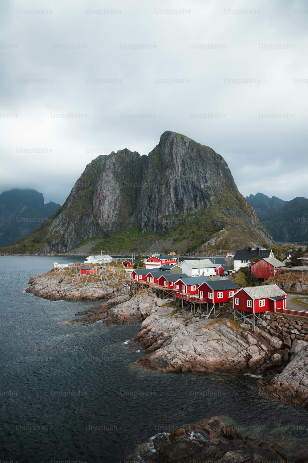 a group of red buildings sitting on top of a rocky shore