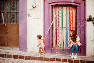 two little girls playing with a kite in front of a building