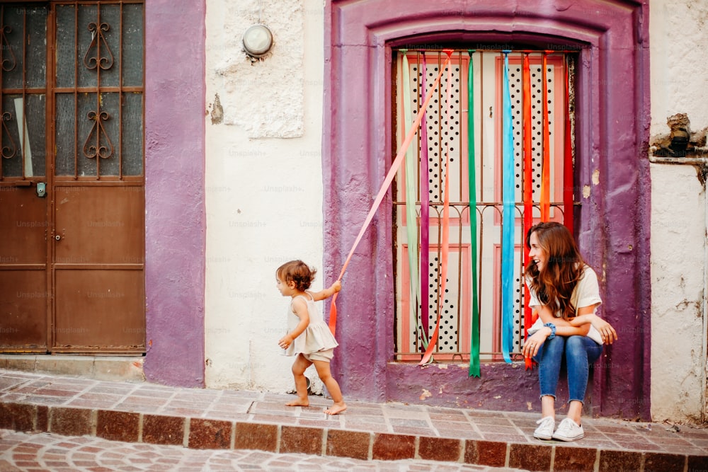 Zwei kleine Mädchen spielen mit einem Drachen vor einem Gebäude