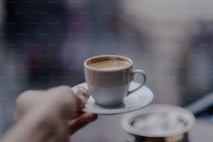 un gros plan d’une personne tenant une tasse de café