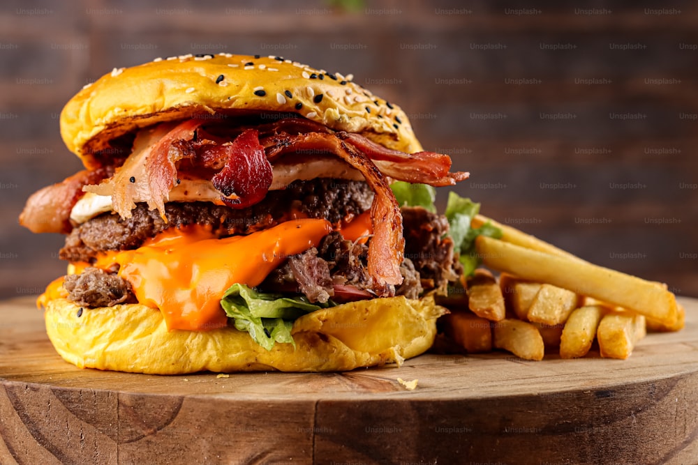 un cheeseburger au bacon avec des frites sur une table en bois