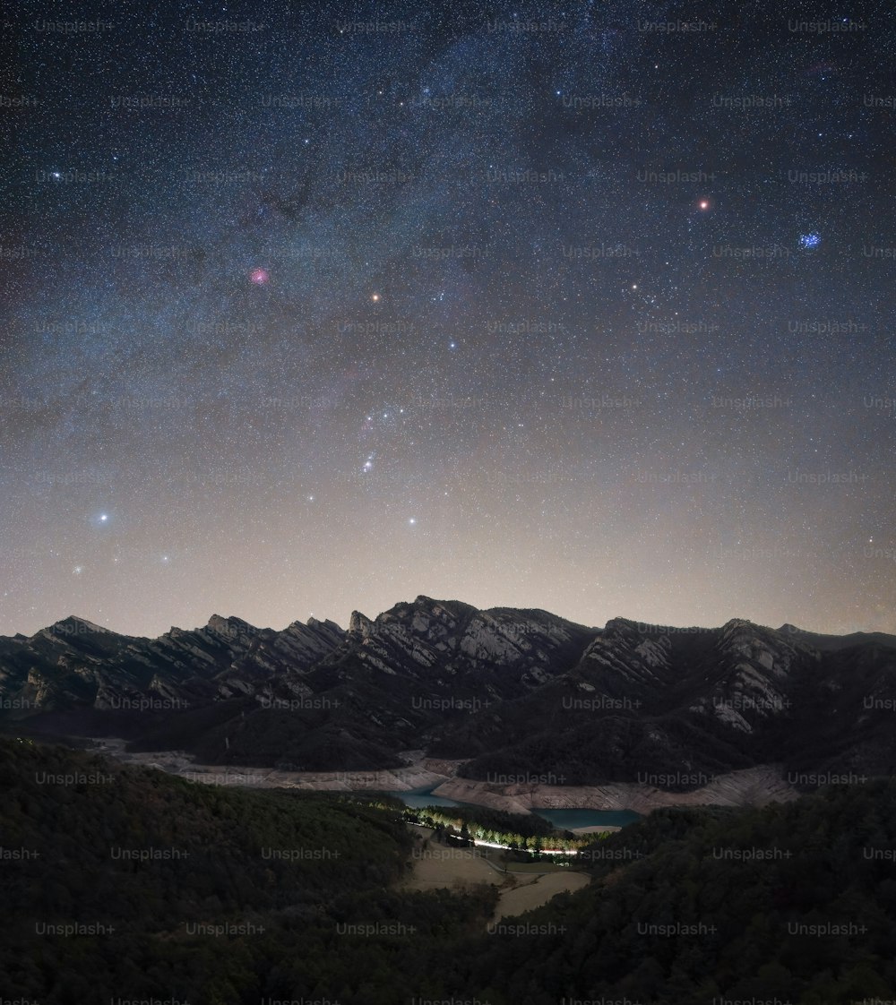 the night sky with stars above a mountain range