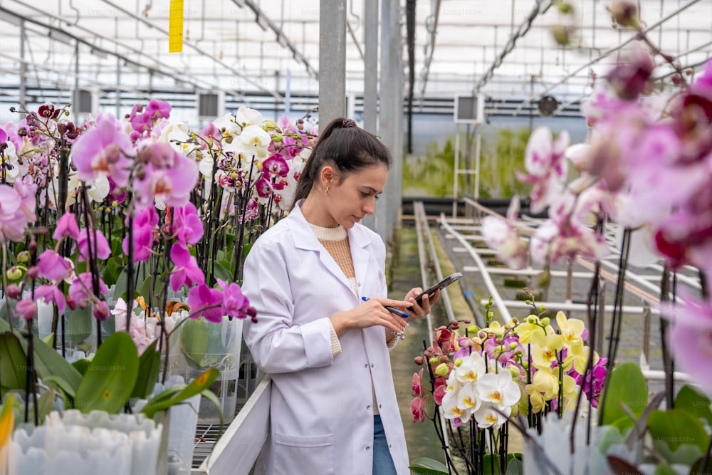 a woman standing in a greenhouse looking at a cell phone