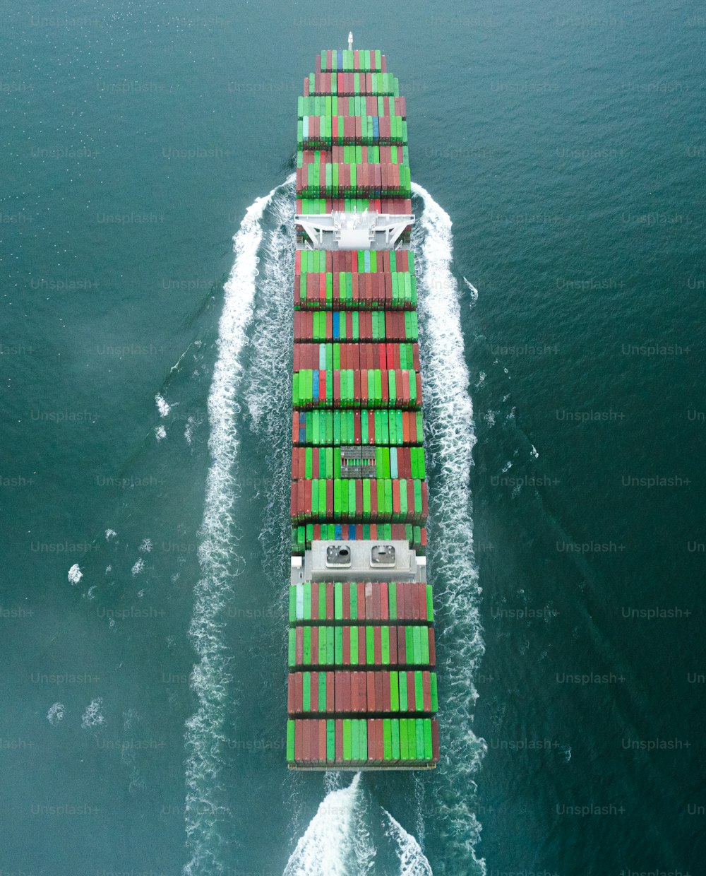 a large green and red container ship in the ocean