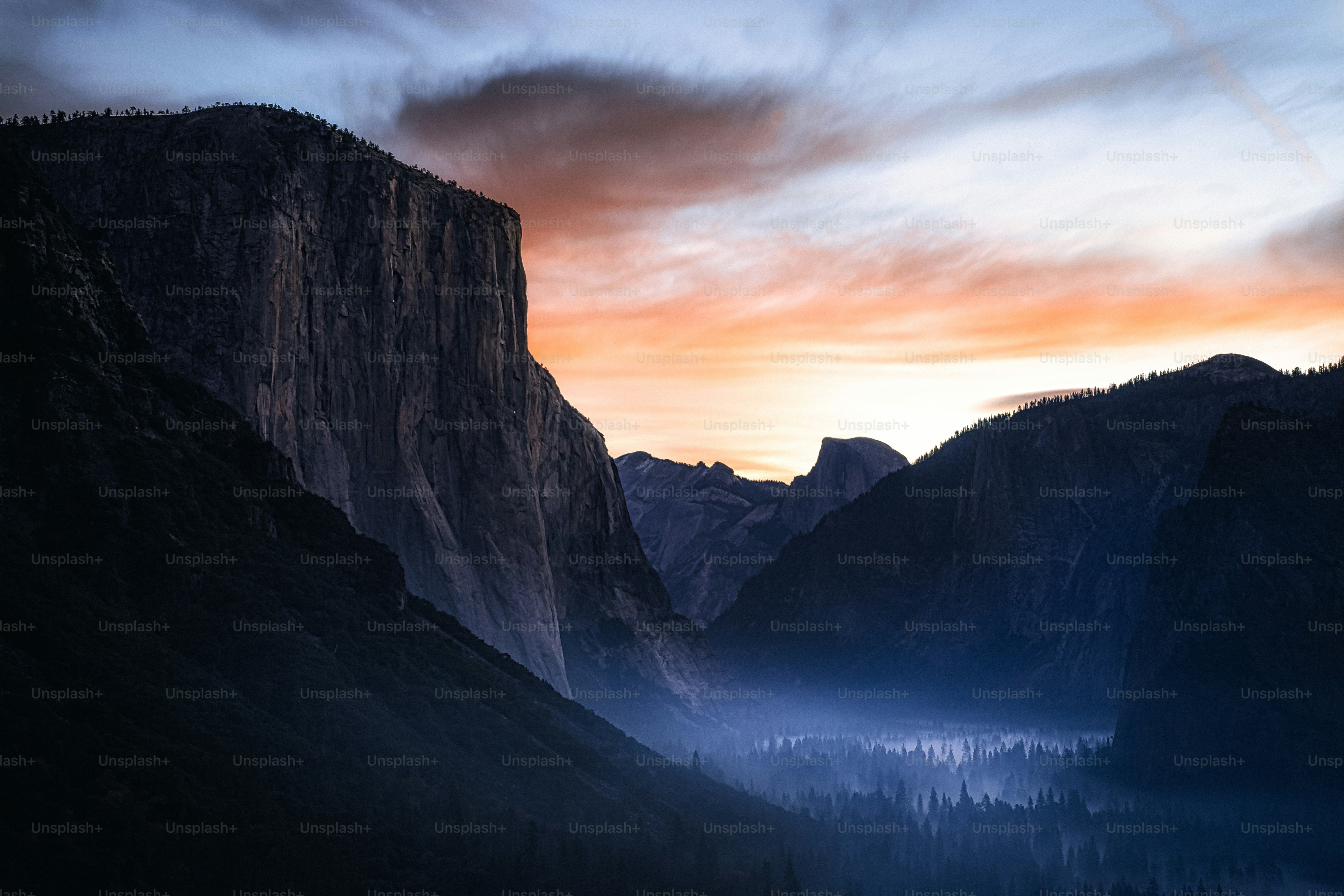 The sun is setting over a valley with mountains in the background photo ...
