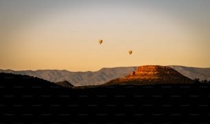 a couple of hot air balloons flying over a mountain