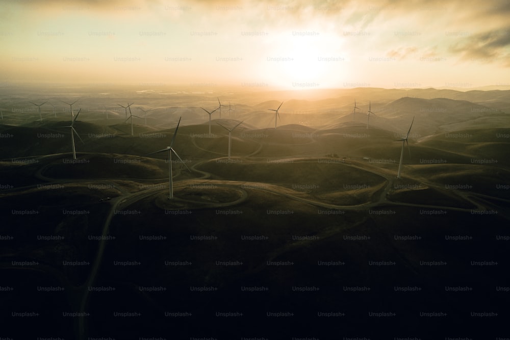 a group of windmills on a hill at sunset