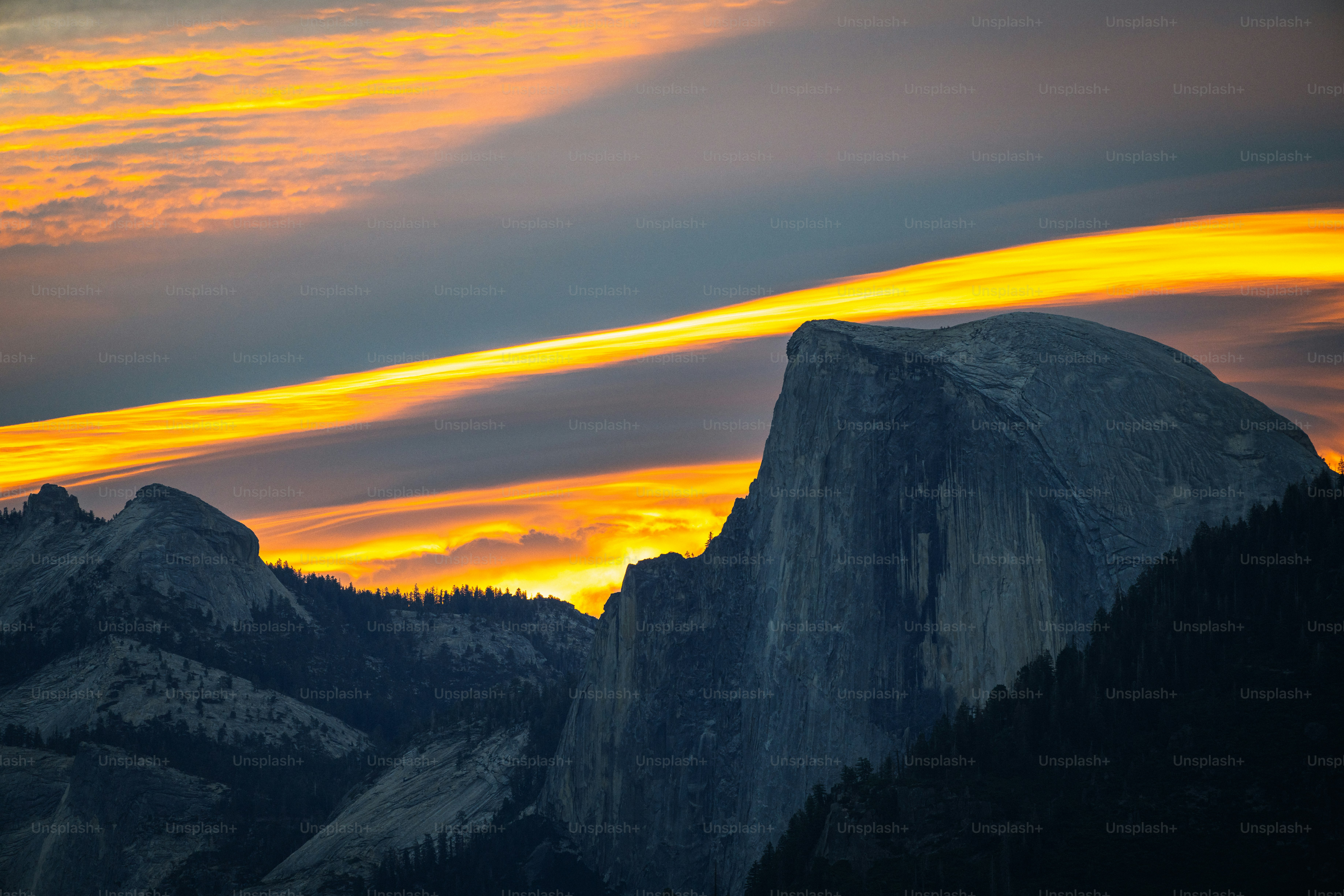 the sun is setting over the mountains and trees