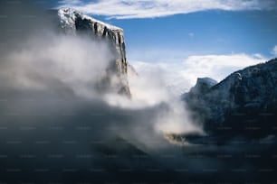 uma montanha muito alta coberta de nevoeiro e nuvens