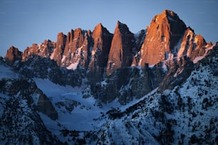 a mountain range covered in snow at sunset