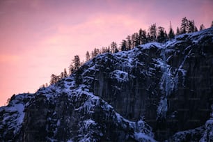 a very tall mountain covered in snow under a pink sky