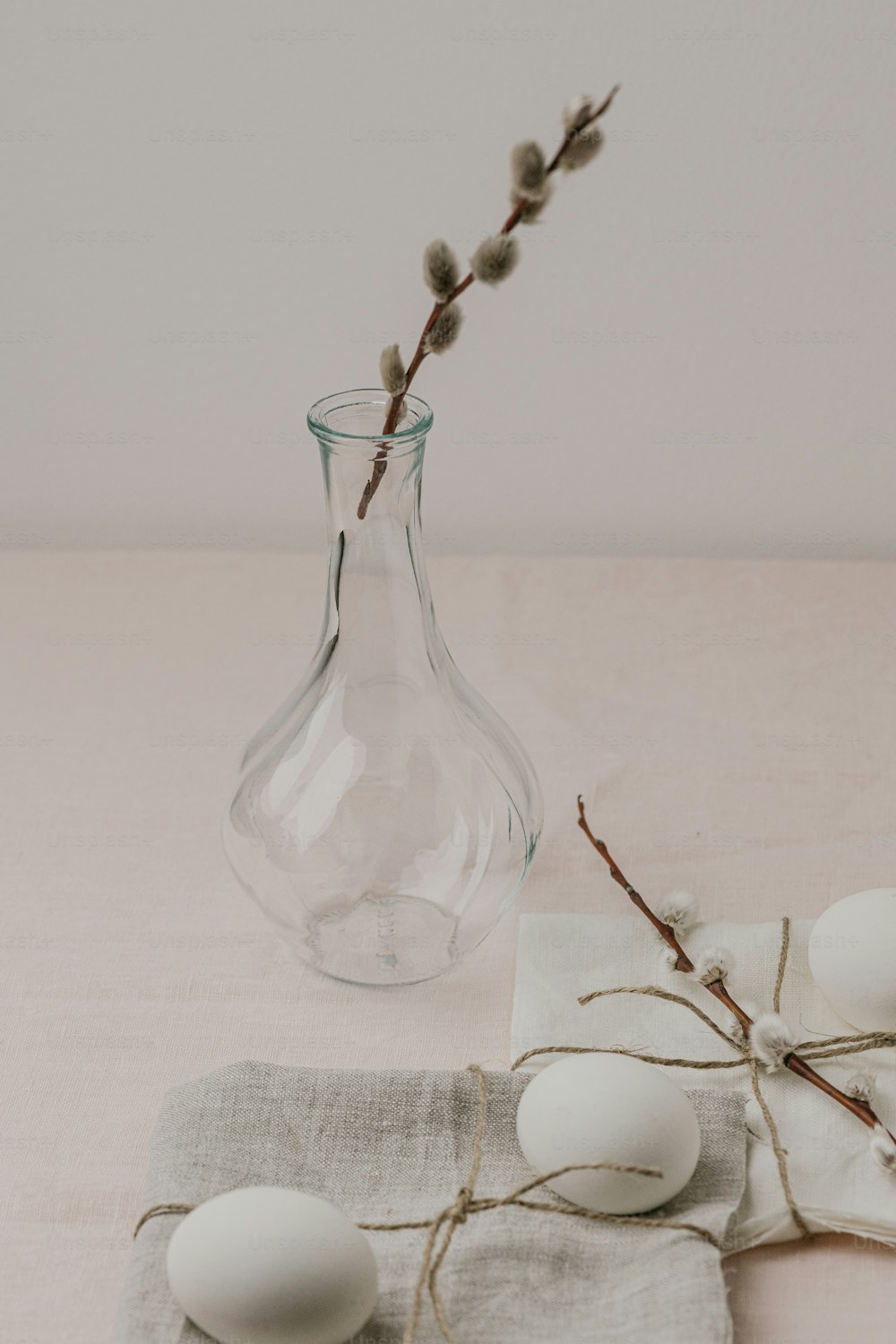 a glass vase with a twig sticking out of it