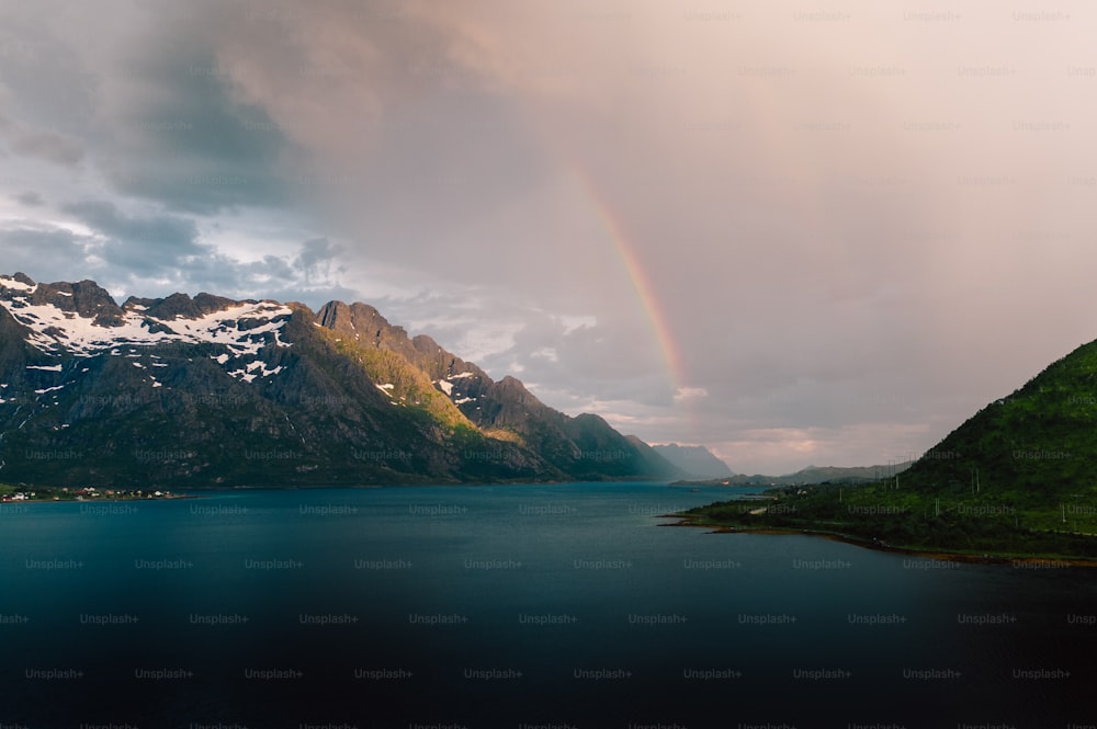 a rainbow in the sky over a mountain lake