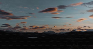 a sunset with clouds and mountains in the background