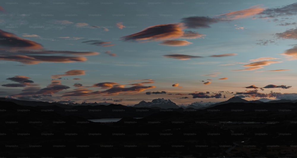 Un tramonto con nuvole e montagne sullo sfondo