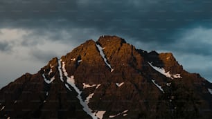 a very tall mountain covered in snow under a cloudy sky