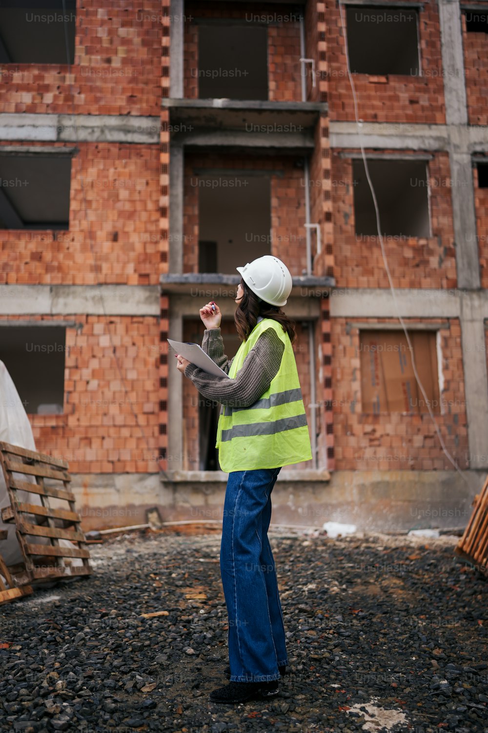 um trabalhador da construção civil em pé na frente de um edifício de tijolos