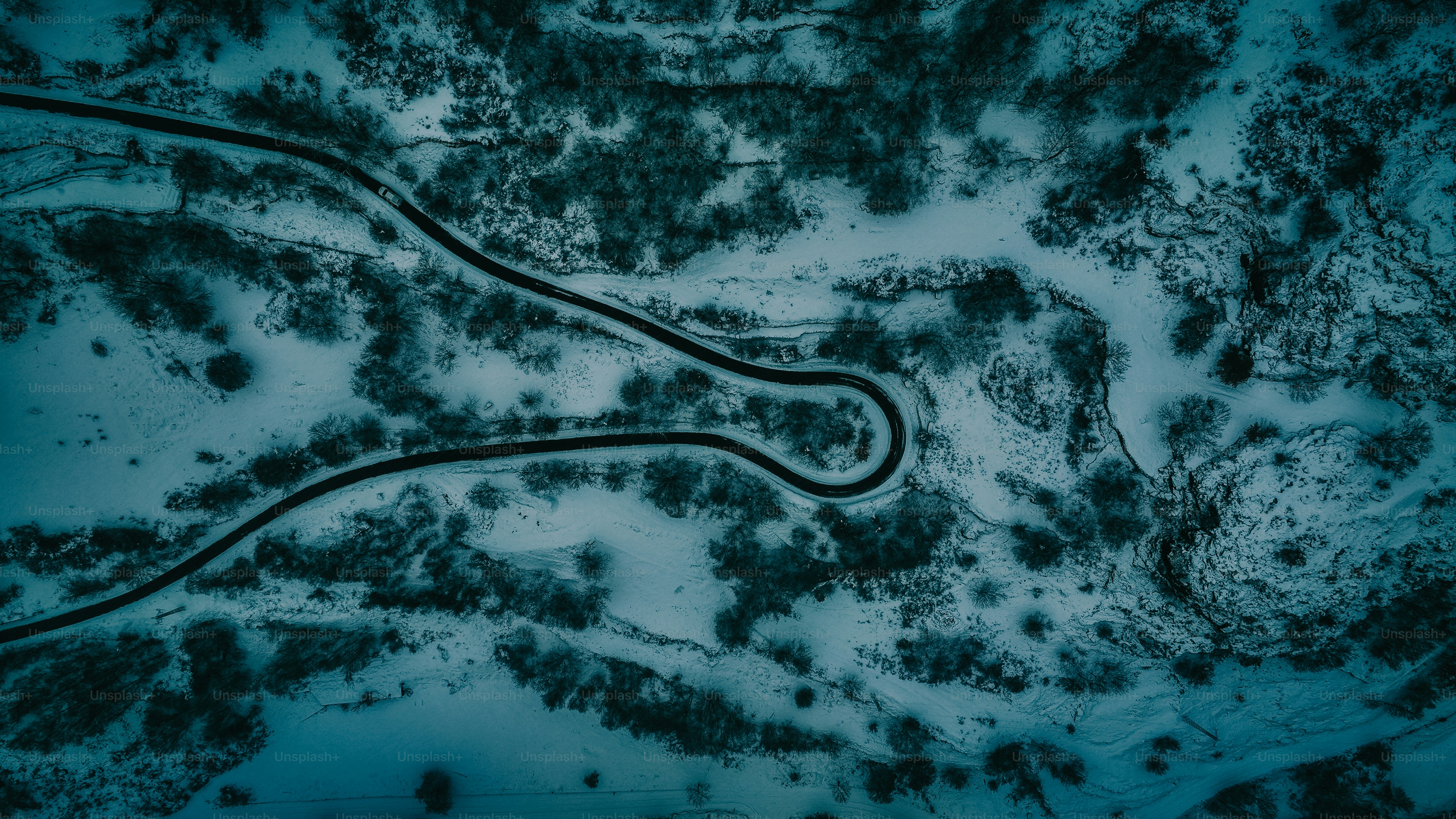 an aerial view of a winding road in the snow