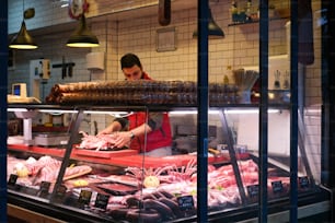 a man working behind the counter of a butcher shop