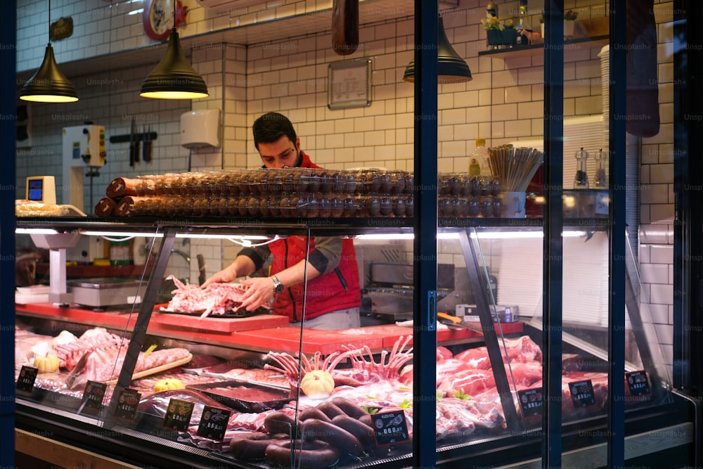 a man working behind the counter of a butcher shop