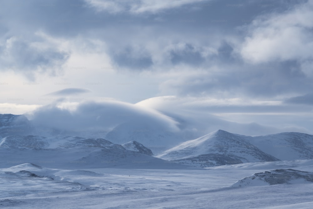 a snow covered mountain range under a cloudy sky