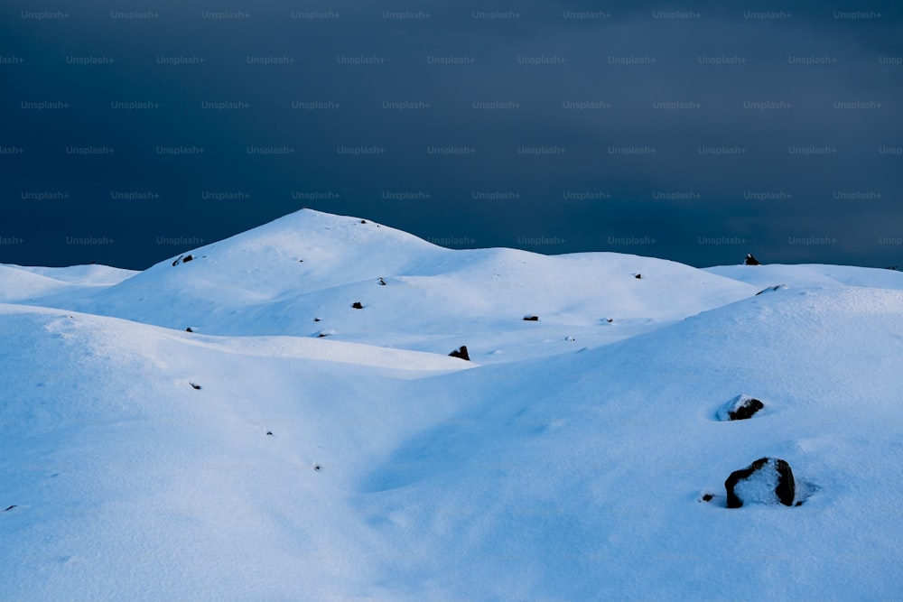 um grupo de colinas cobertas de neve sob um céu nublado