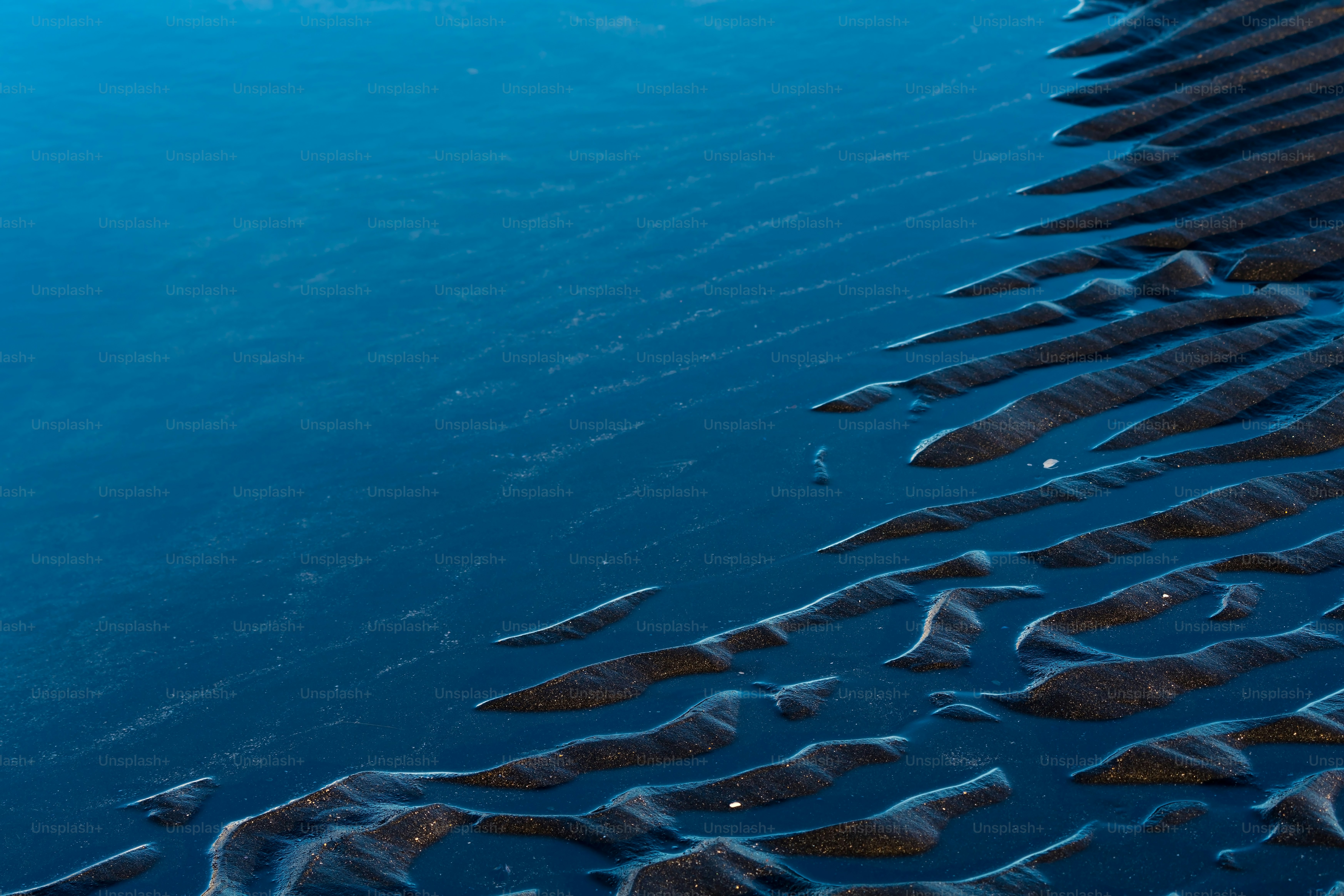 footprints in the sand on a beach next to the water