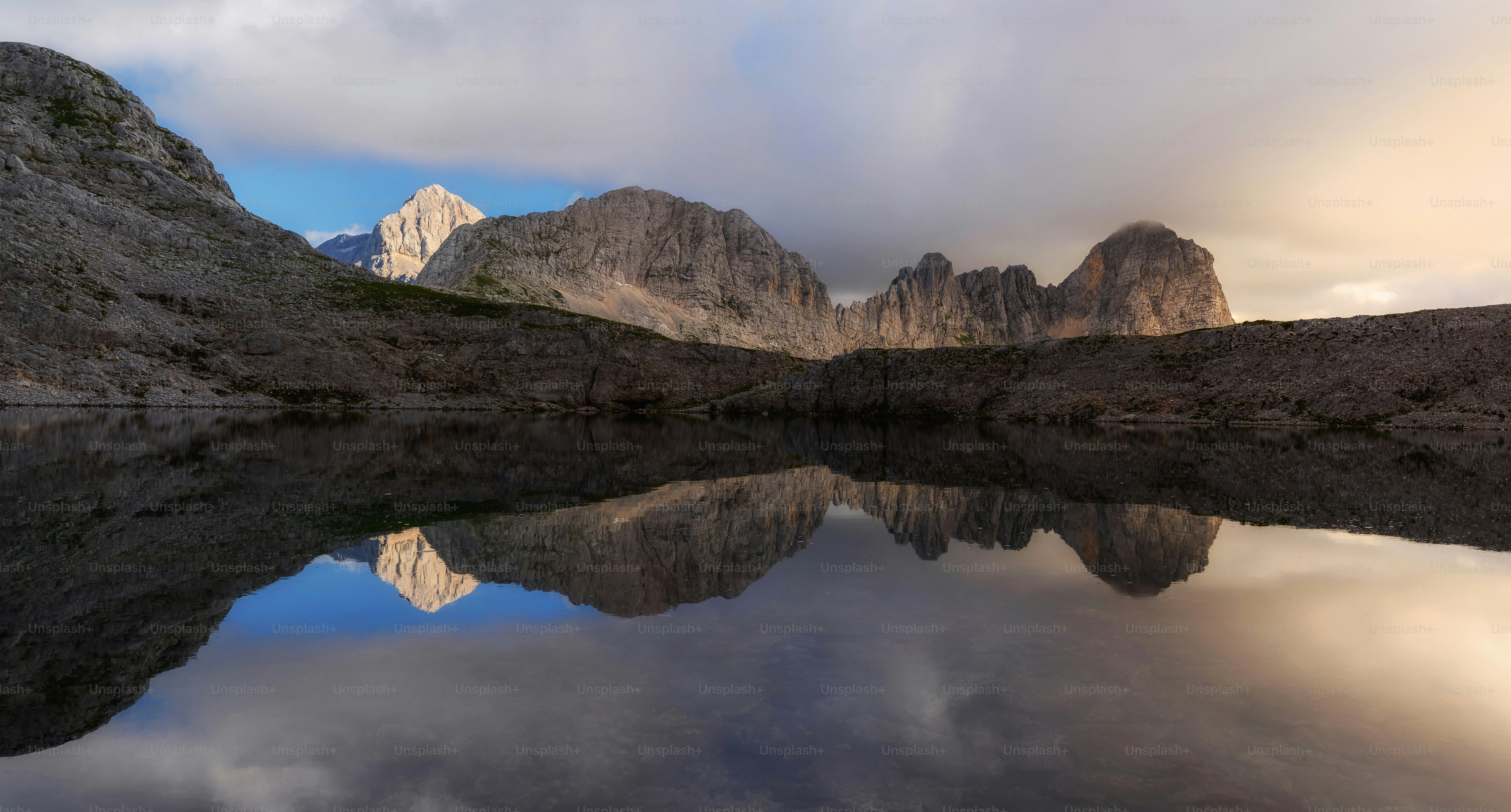 a mountain range is reflected in the still water of a lake