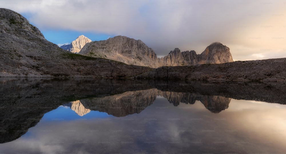 uma cordilheira é refletida na água parada de um lago