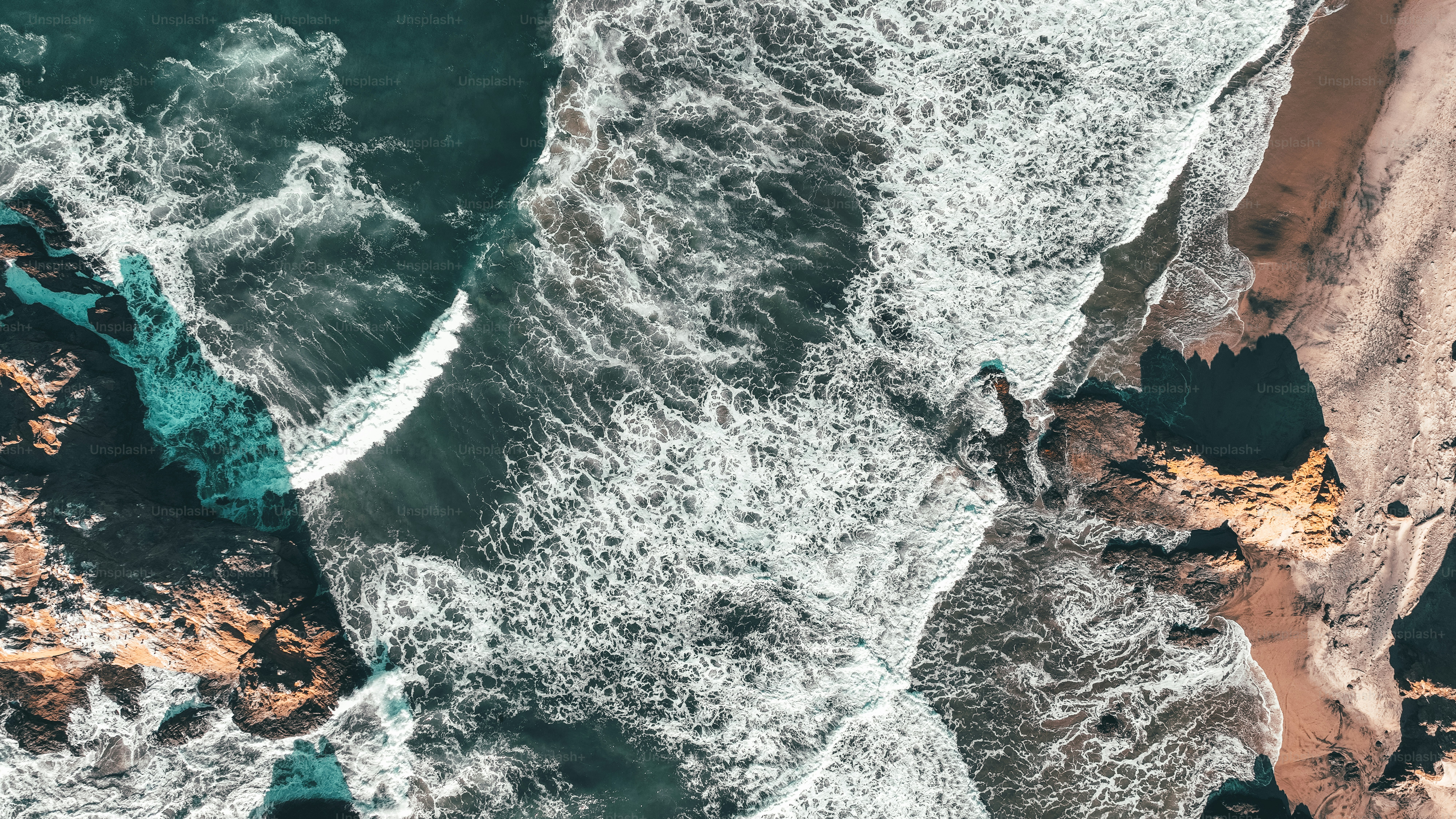 an aerial view of a beach with waves crashing on the shore