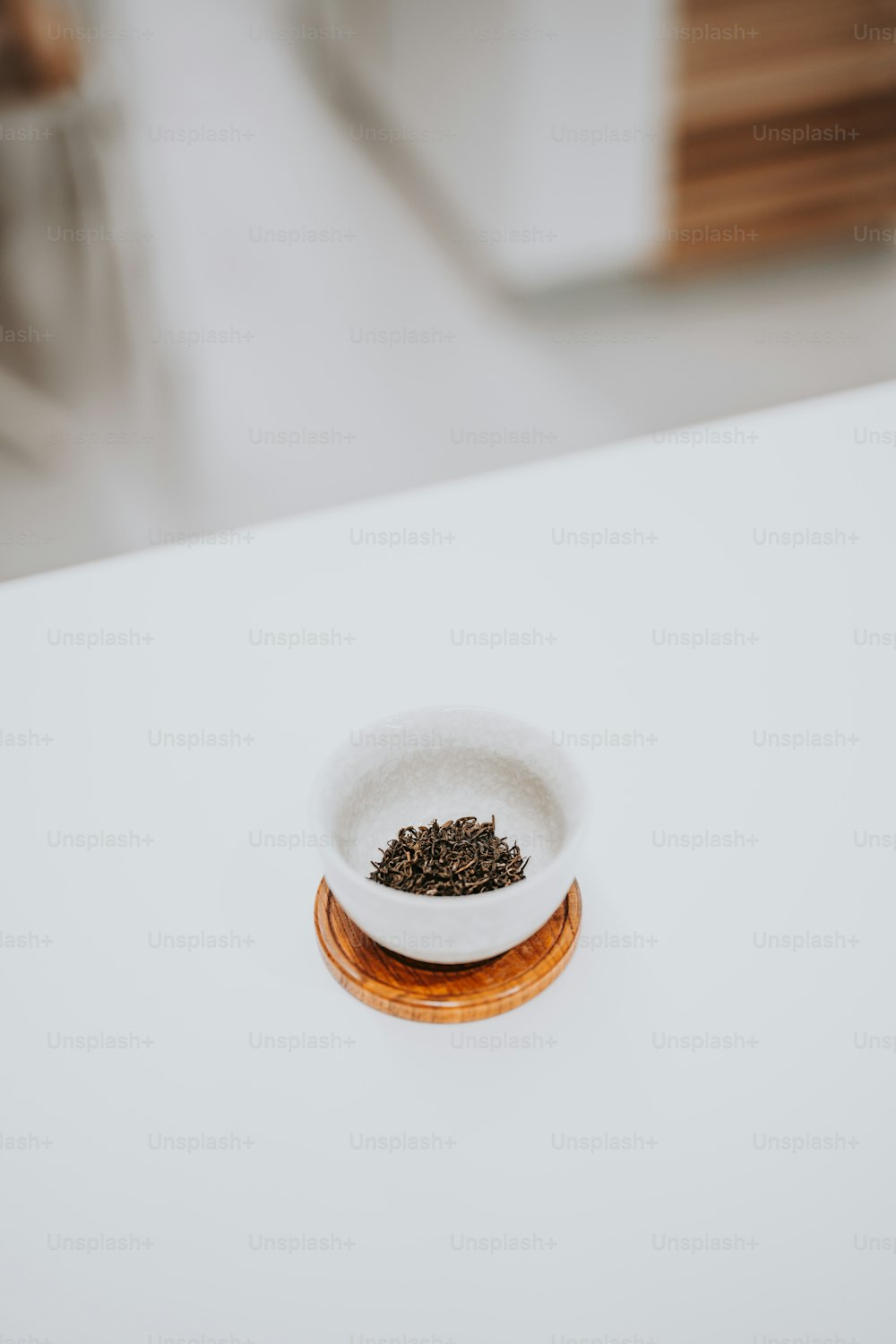 uma tigela branca cheia de chá sentada em cima de uma mesa branca
