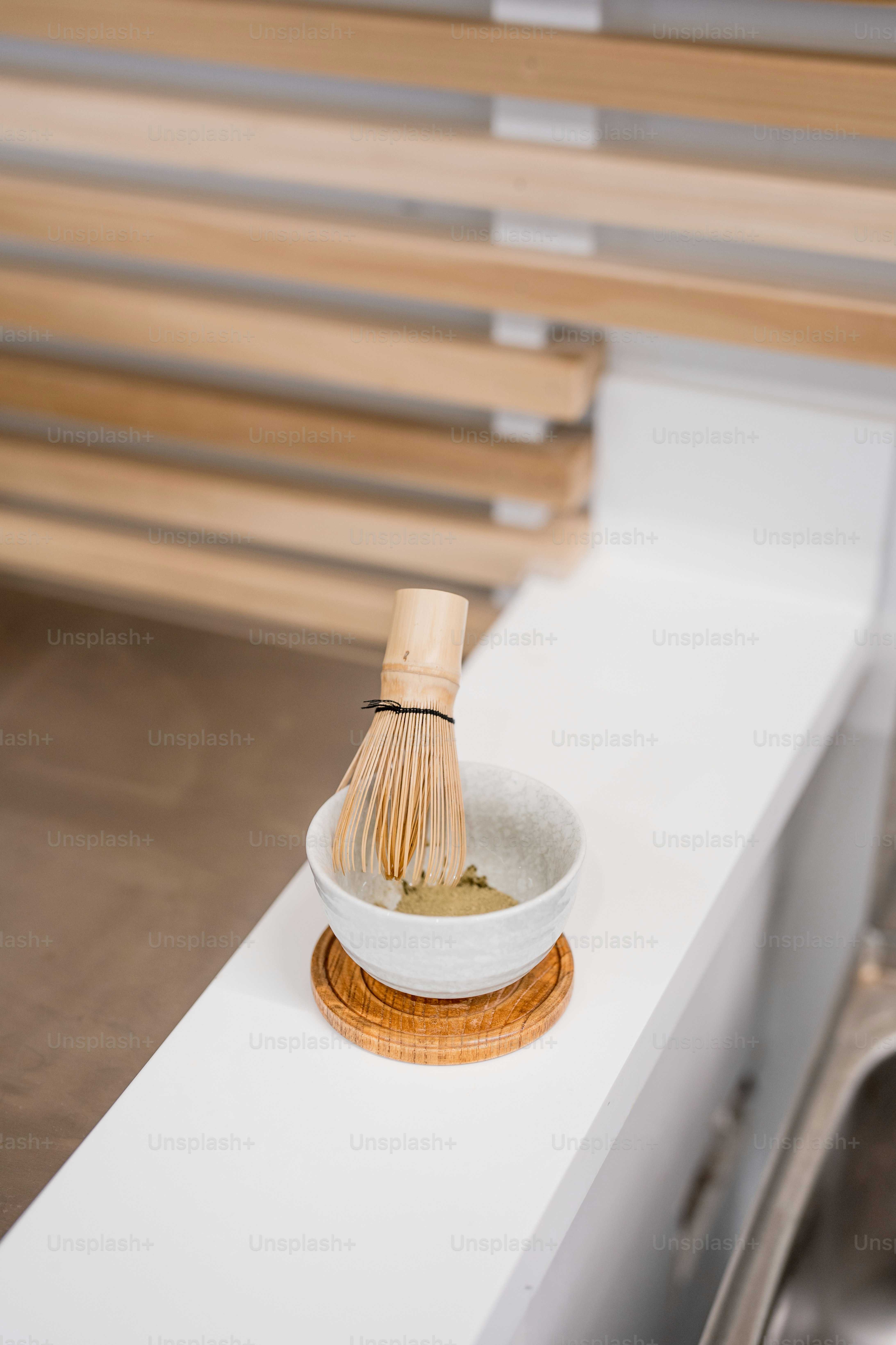 a wooden whisk in a white bowl on a counter