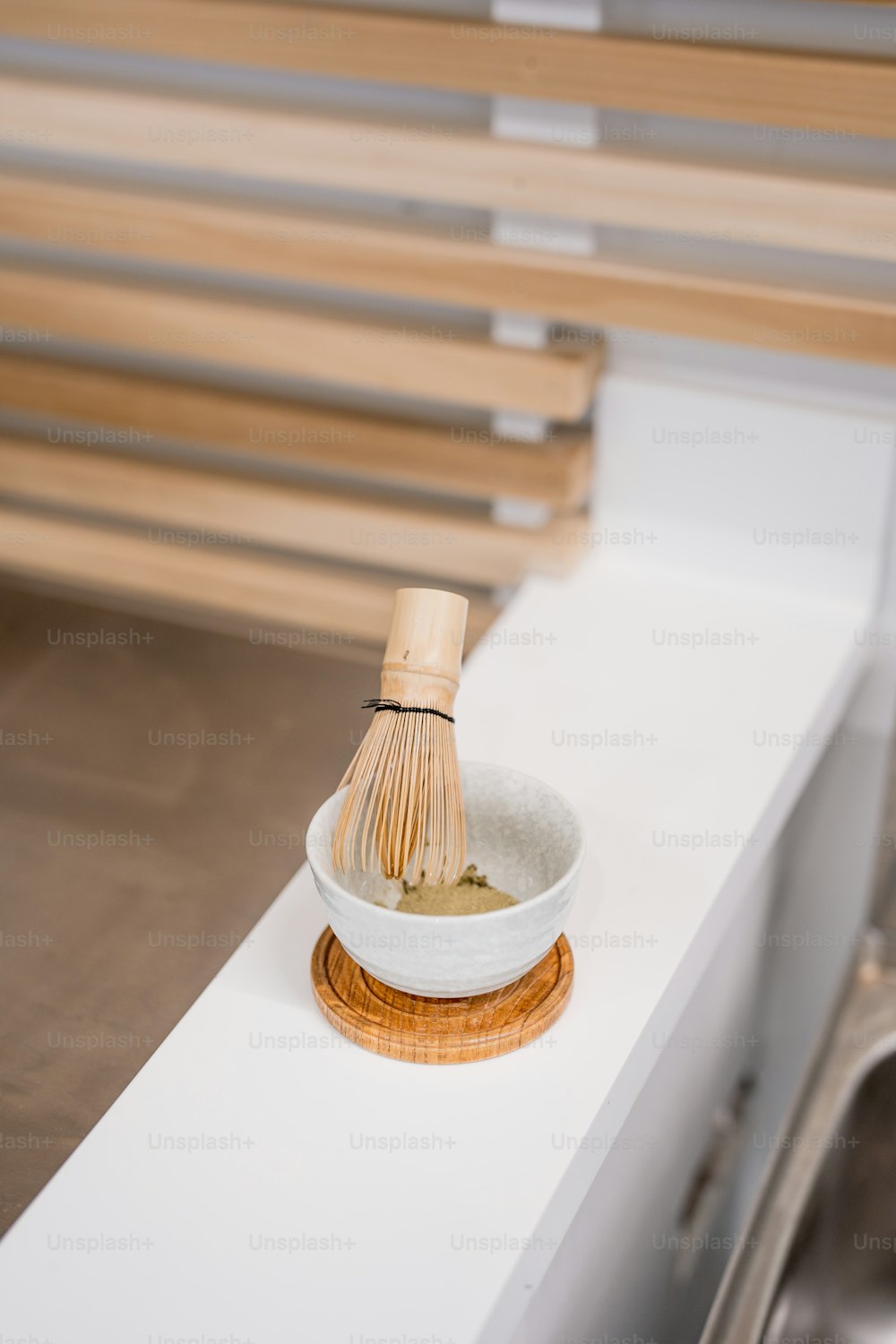 un batidor de madera en un tazón blanco en un mostrador