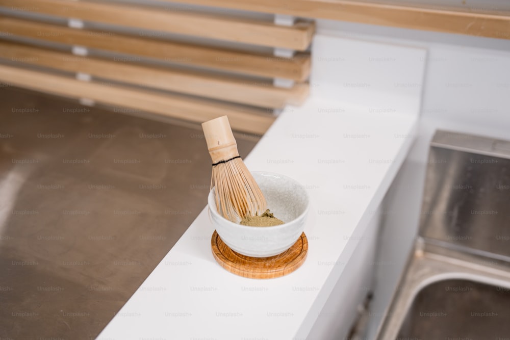 a wooden whisk in a white bowl on a counter