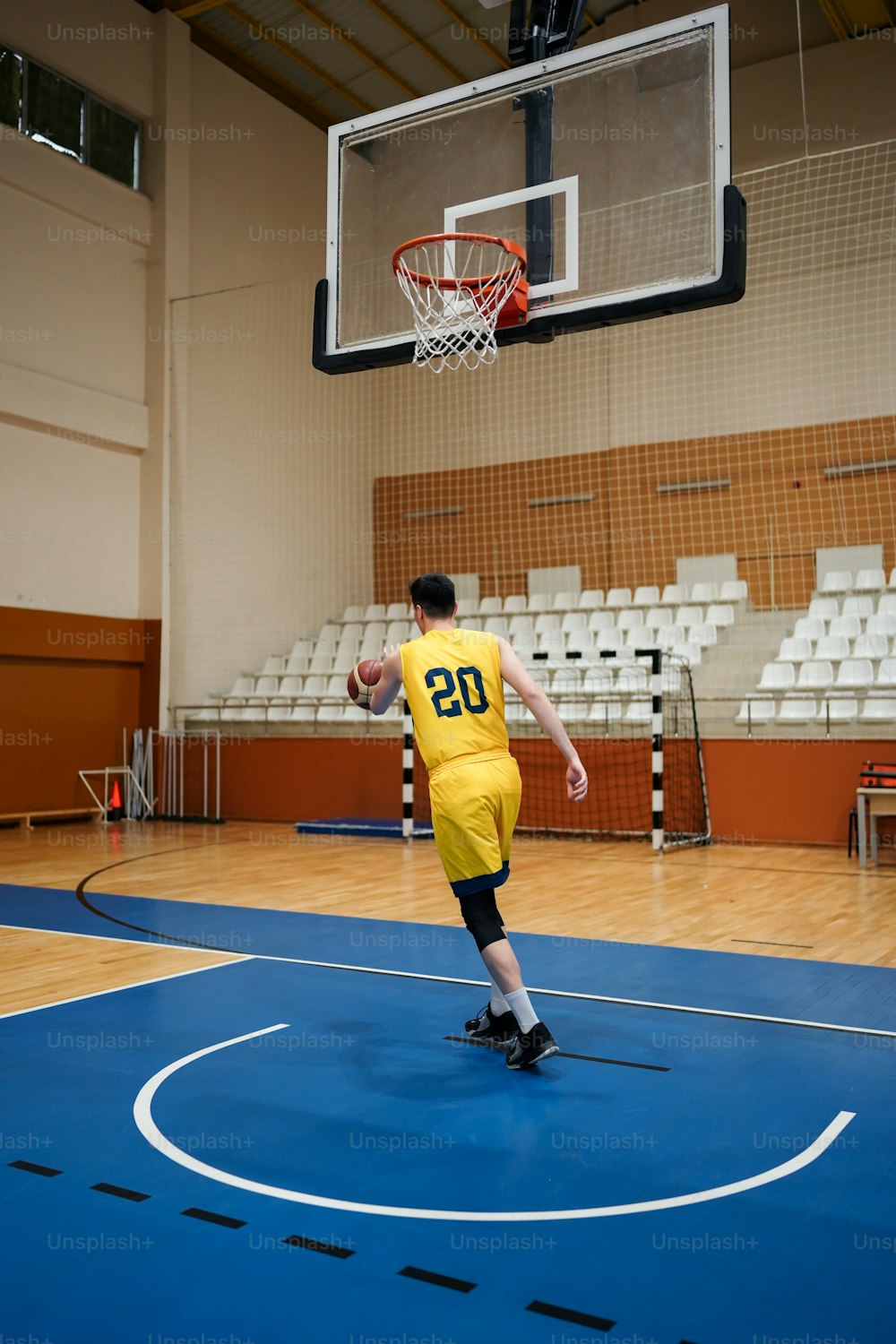 a man in a yellow jersey is playing basketball