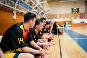 a group of men sitting on top of a basketball court