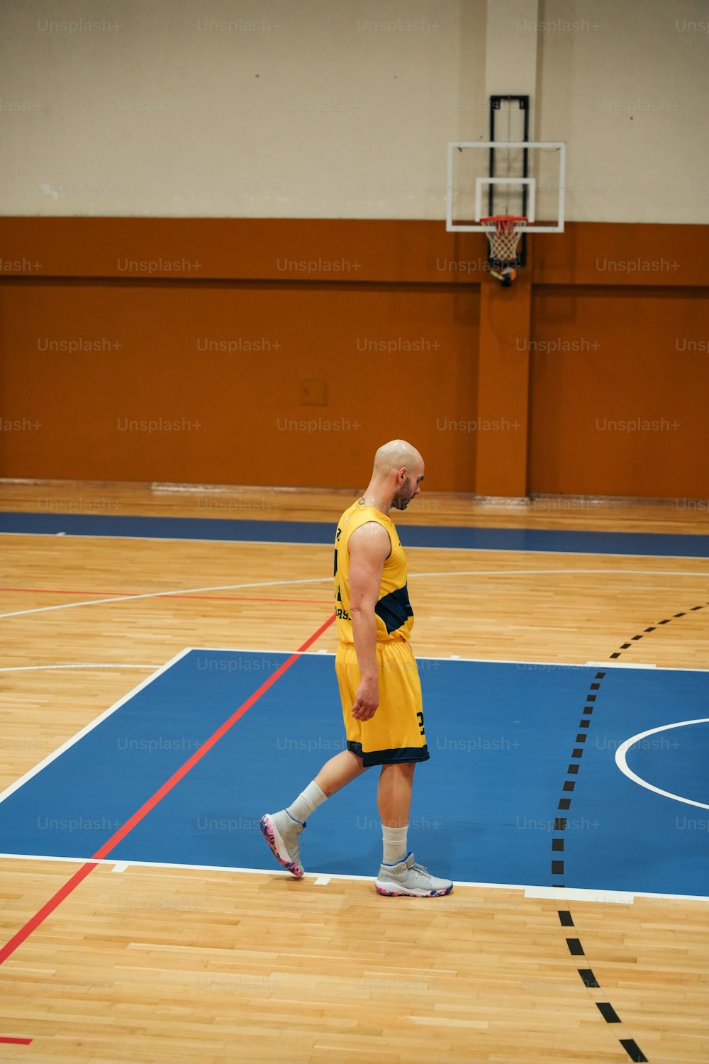 Un hombre con uniforme amarillo en una cancha de baloncesto