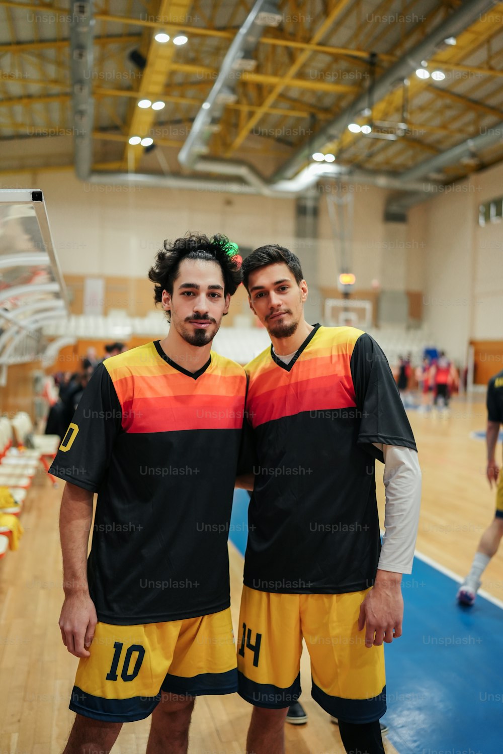 um casal de homens de pé um ao lado do outro em uma quadra de basquete