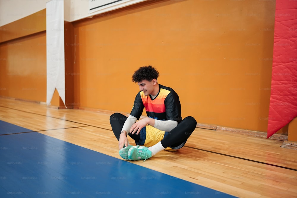 a young man sitting on the floor tying his shoes