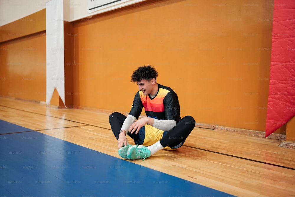 a young man sitting on the floor tying his shoes