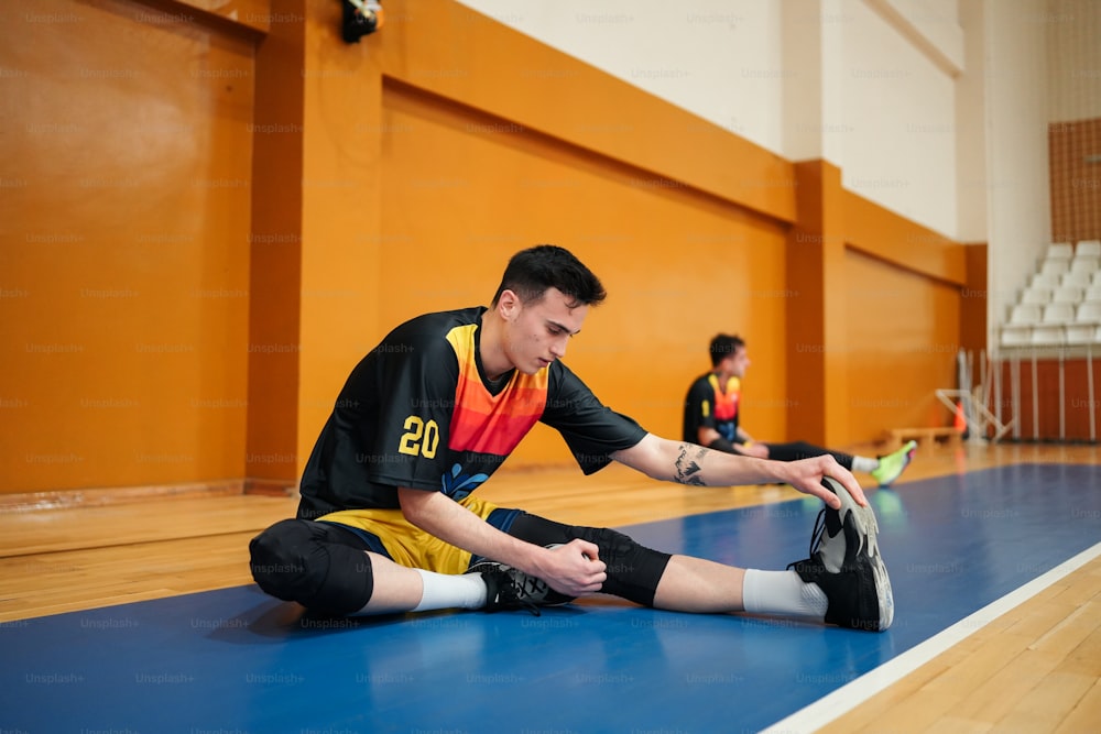 a man sitting on the floor in a gym