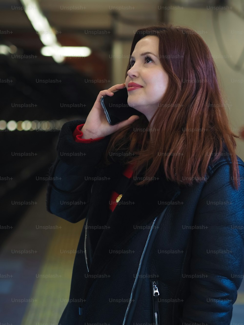 a woman in a black jacket talking on a cell phone