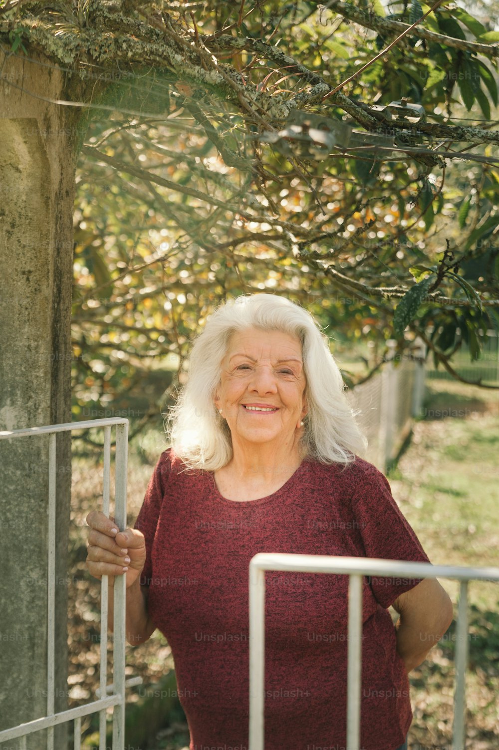 a woman in a red shirt standing next to a tree
